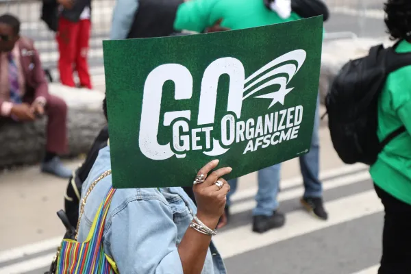 AFSCME member holds a green rally sign that says "Get Organized" AFSCME
