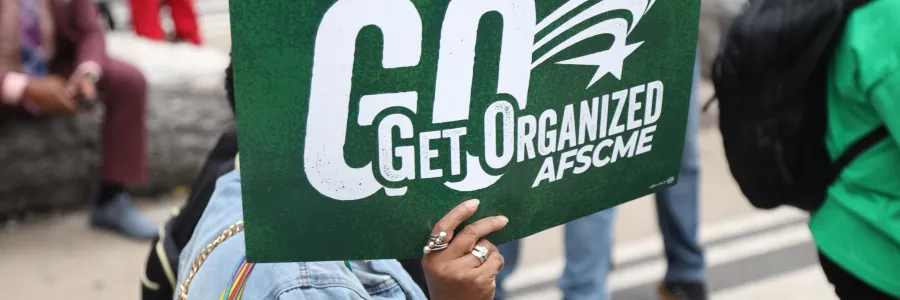 AFSCME member holds a green rally sign that says "Get Organized" AFSCME
